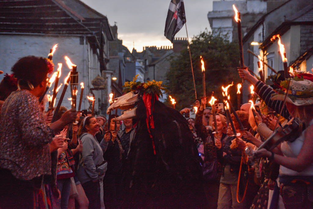 Penglaz, the iconic Cornish ‘Obby Oss’, leading the Golowan Festival Torchlit Parade through the streets of Penzance, with crowds, lanterns and musicians celebrating Mazey Eve