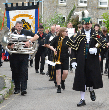 Golowan Festival Civic Parade processing through the streets of Penzance, featuring colourful banners and community groups, photographed by Greg Huckfield.
